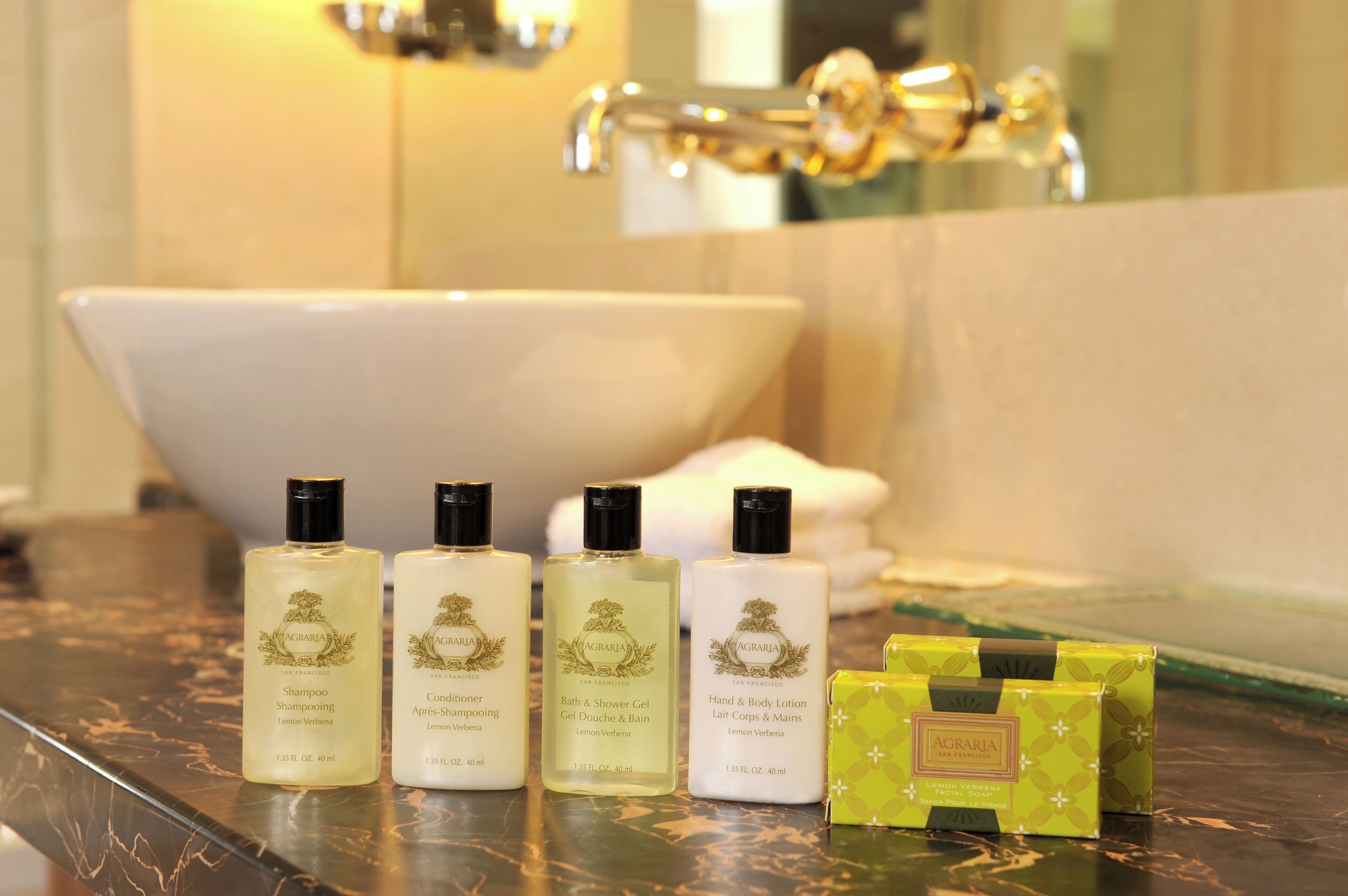 A bathroom with a bathtub, three bottles of AGRARIA products, and a green box on the counter.