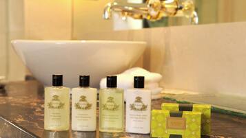 A bathroom with a bathtub, three bottles of AGRARIA products, and a green box on the counter.