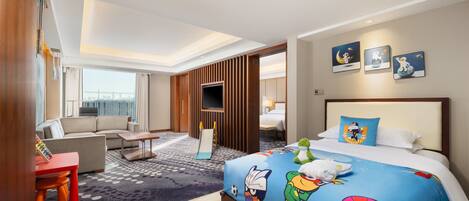A hotel room with a large bed, a sofa, a desk, and a TV.