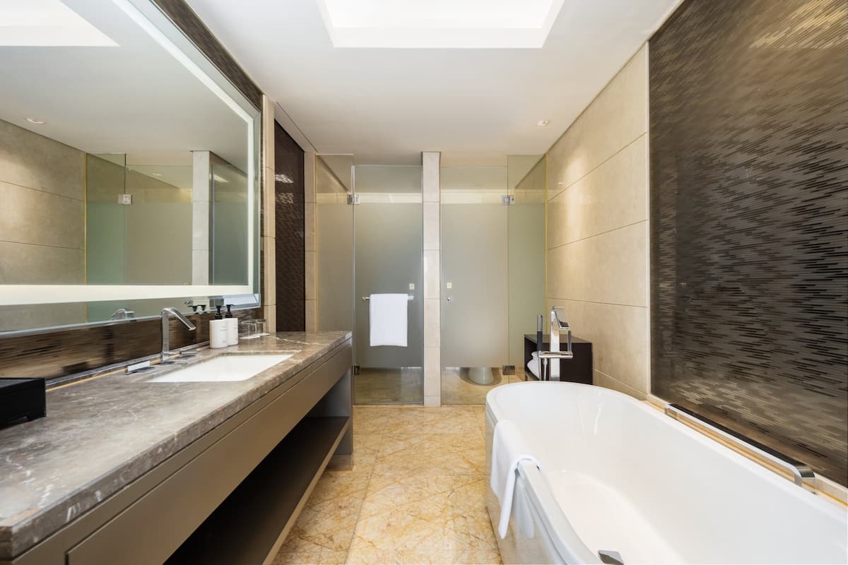 Un baño moderno con un espejo grande, dos lavamanos, una ducha y una bañera.