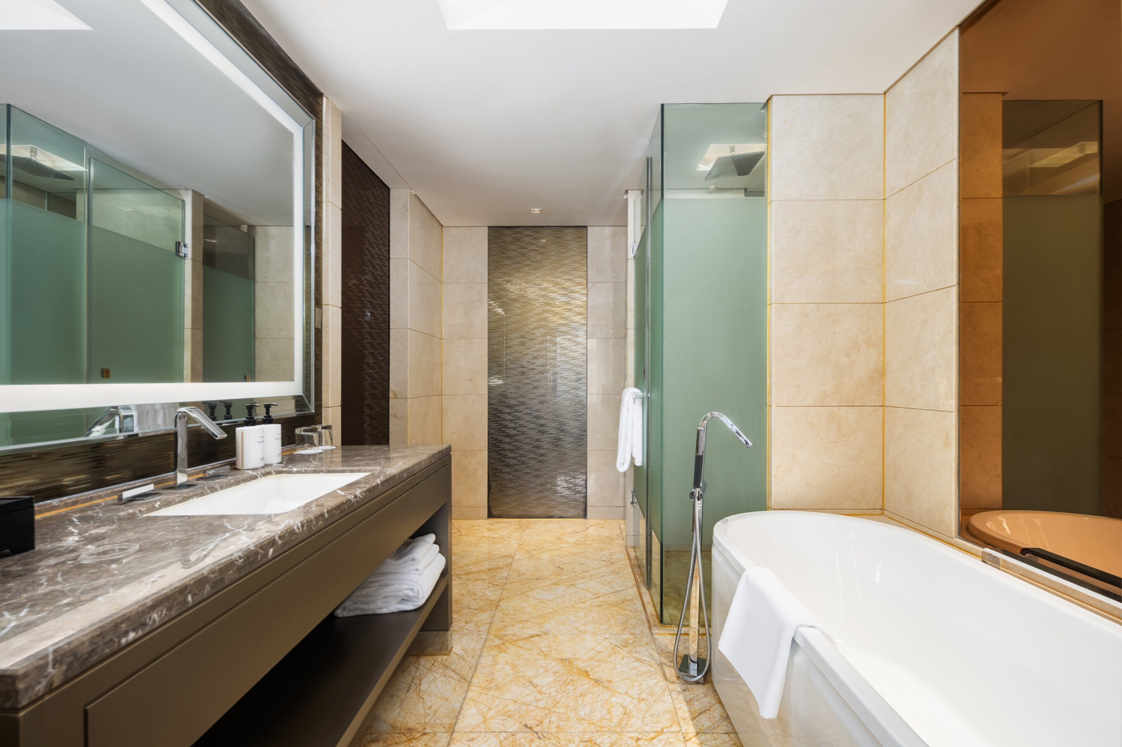 A modern bathroom with a double sink, a large mirror, a glass shower enclosure, and a bathtub.