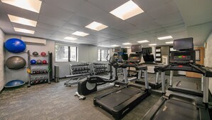 A gym with treadmills, elliptical machines, and various weights.