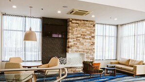A modern living room with a stone accent wall, a sofa, a coffee table, and a dining area with chairs and a table.