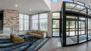 A spacious lobby with a stone wall, seating area, and a large glass door leading outside.