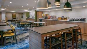 A modern hotel lobby with a central bar area, seating arrangements, and a tiled backsplash.