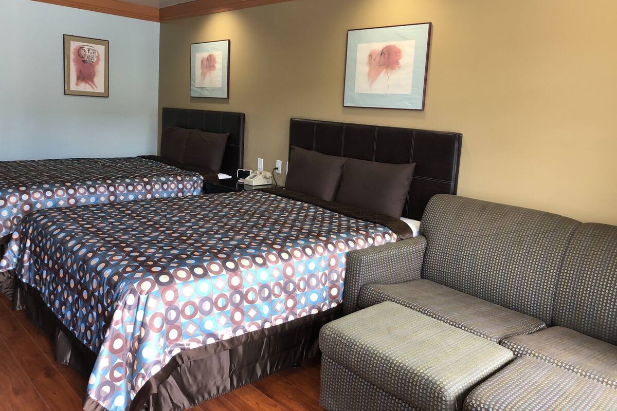 A hotel room with two beds, a sofa, and artwork on the walls.