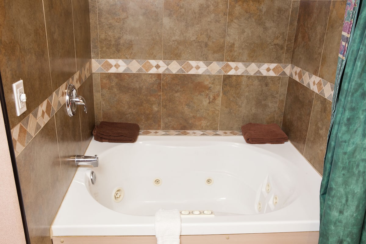 A modern bathroom with a large bathtub, a shower, and a toilet.