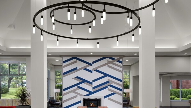 A spacious lobby with a modern chandelier, a patterned wall, and comfortable seating areas.
