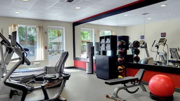 Une salle de sport équipée de matériel d’exercice, avec un ballon rouge pour les exercices et une vue sur l’extérieur grâce à de grandes fenêtres.