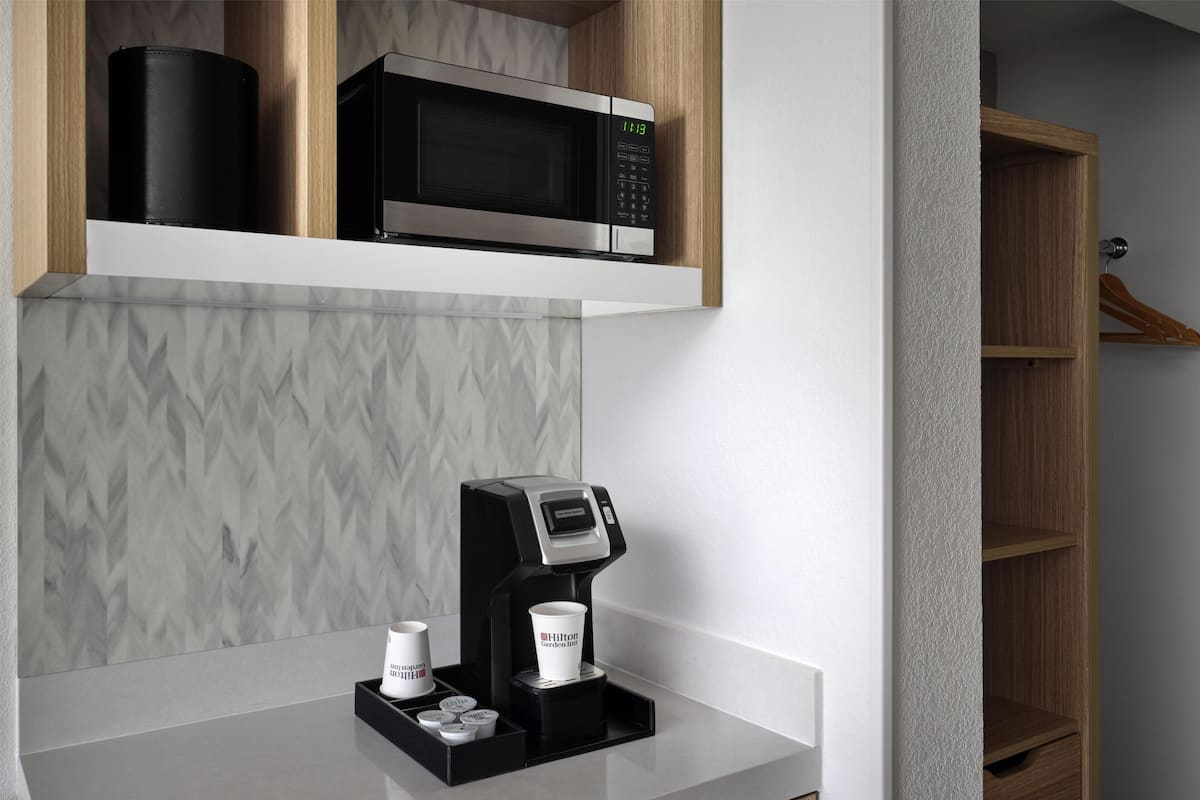 Une cuisine moderne équipée d’un four à micro-ondes, d’une machine à café et d’étagères de rangement.
