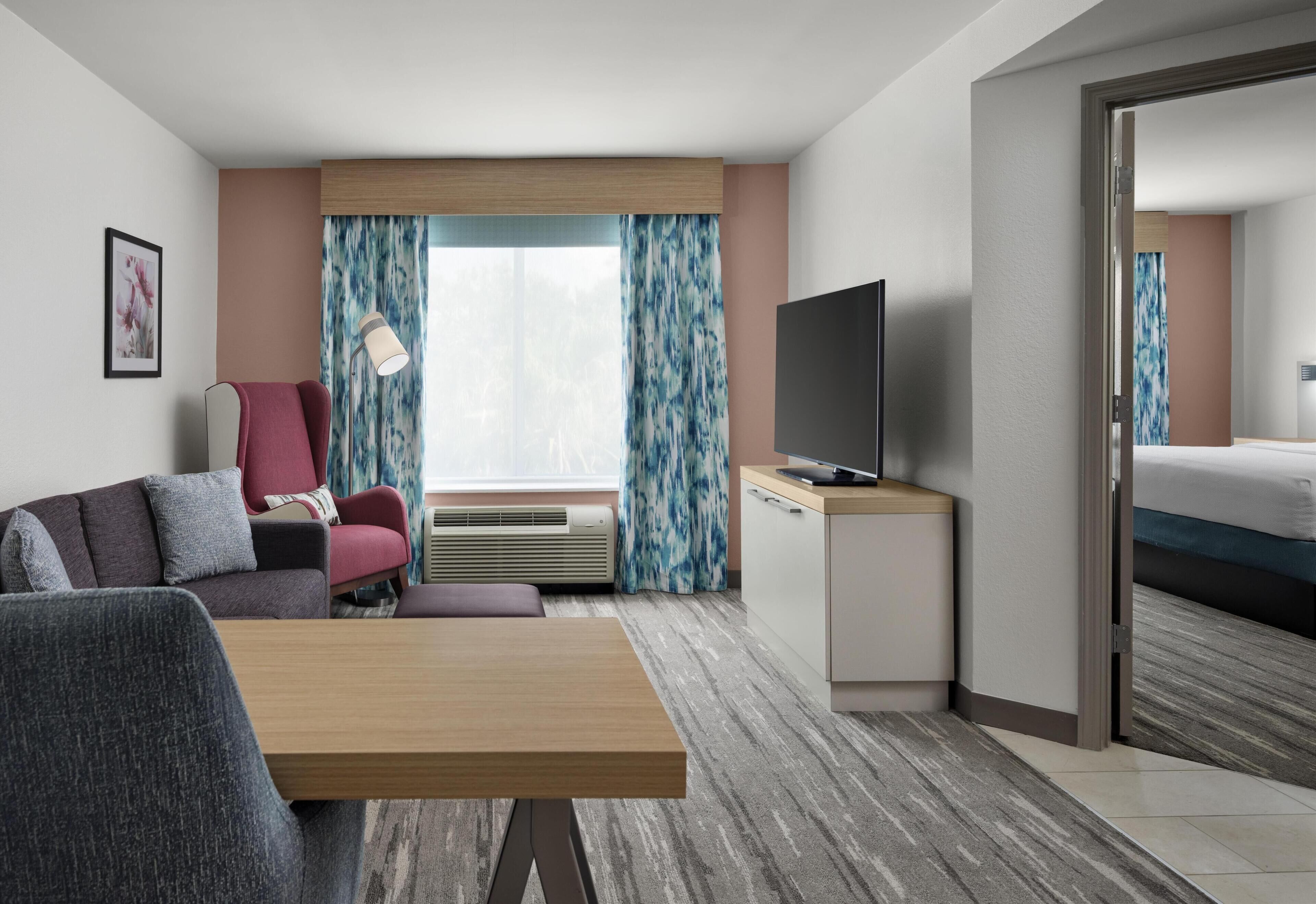 Quarto de hotel com sofá, televisão, escrivaninha e cama.
