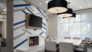 A modern dining area with a fireplace, a flat-screen TV, and a large window.