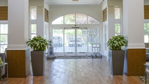 A spacious lobby with wooden flooring, large potted plants, and hanging pendant lights. - Hilton Garden Inn Napa (Napa)
