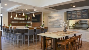 A modern kitchen with a bar area, wooden bar stools, and a menu board. - Hilton Garden Inn Napa (Napa)