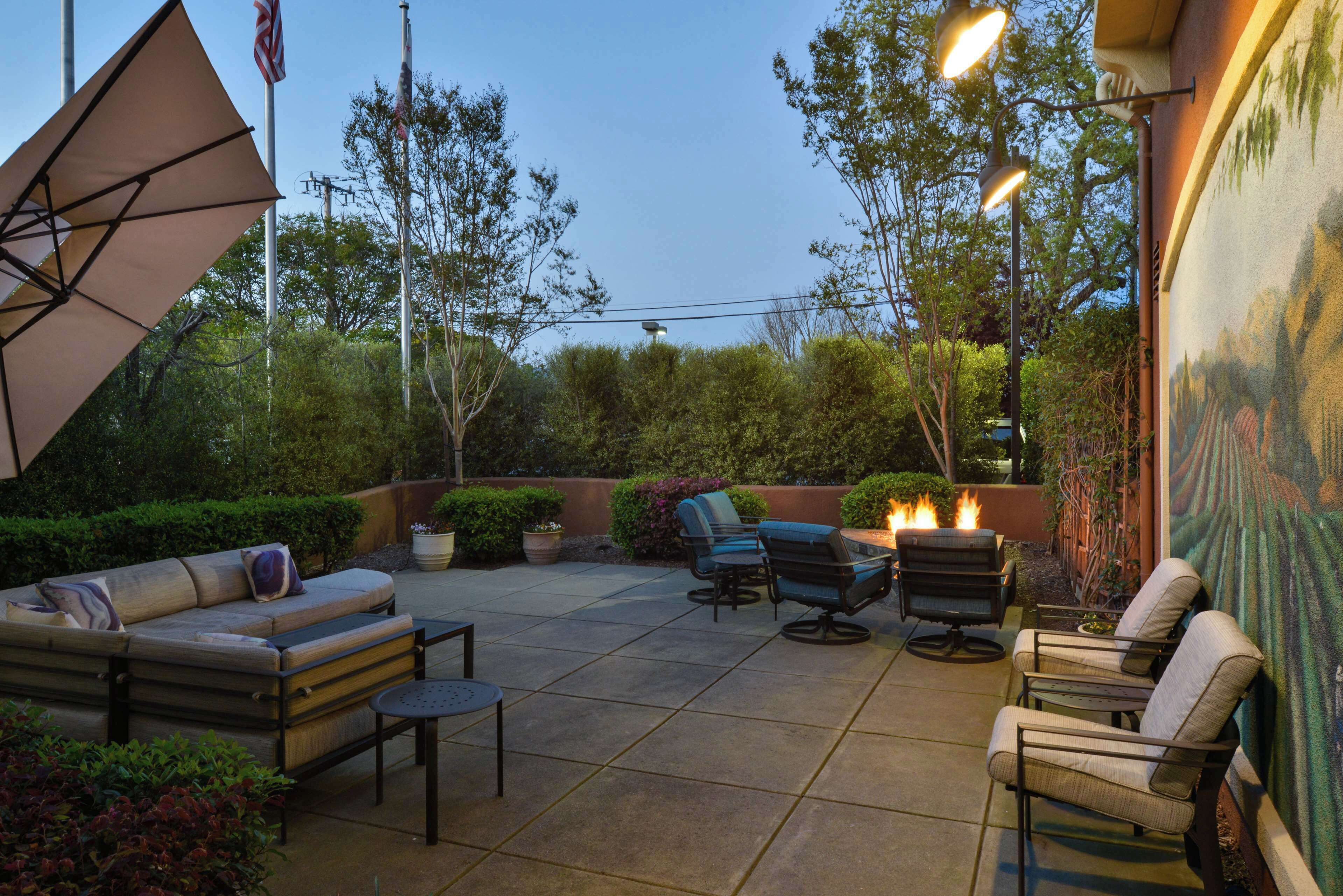 Une terrasse extérieure avec un canapé, des chaises, une table et un barbecue.