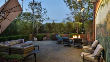 Un patio al aire libre con sofá, sillas, mesa y una parrilla.