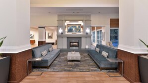 A spacious living room with a fireplace, two sofas, a coffee table, and a large painting on the wall. - Hilton Garden Inn Napa (Napa)