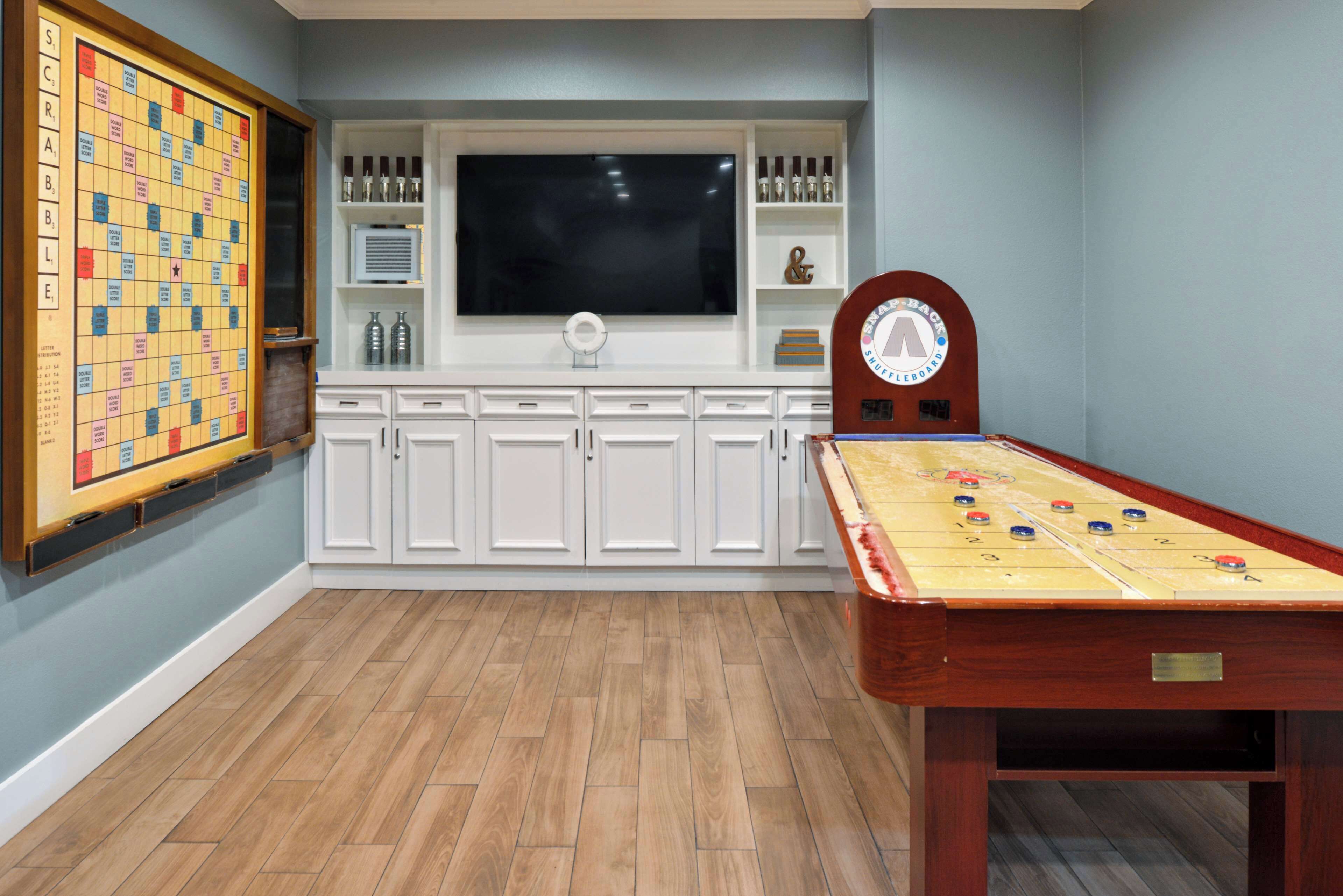 A room with a foosball table, a large television, and a Scrabble board.