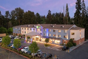 A Holiday Inn Express hotel with a parking lot, multiple floors, and a surrounding forest.