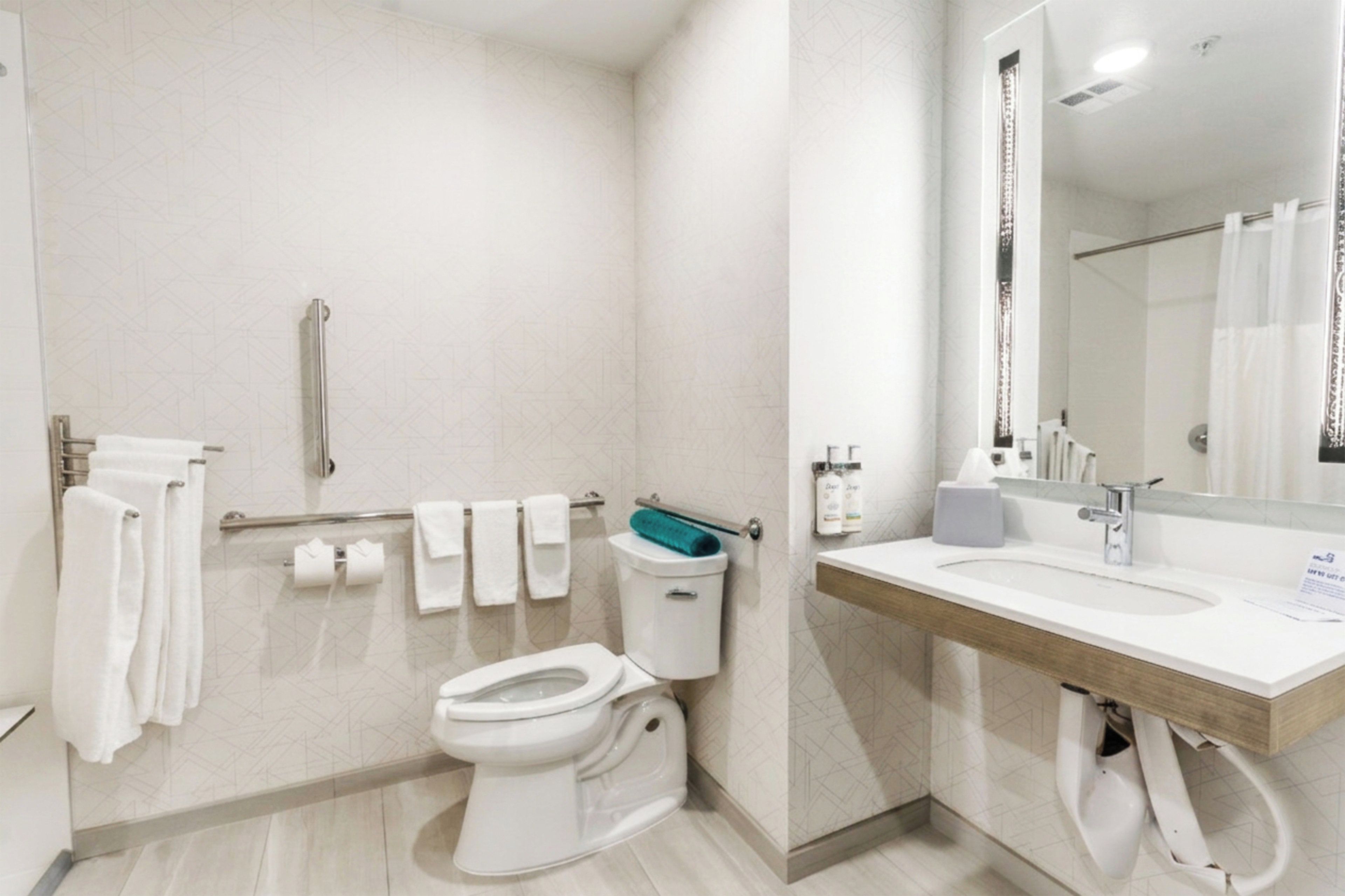 A modern bathroom with a toilet, bidet, hand dryer, and a mirror.