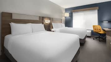 Habitación de hotel con dos camas, un escritorio, una silla y un ventanal grande.