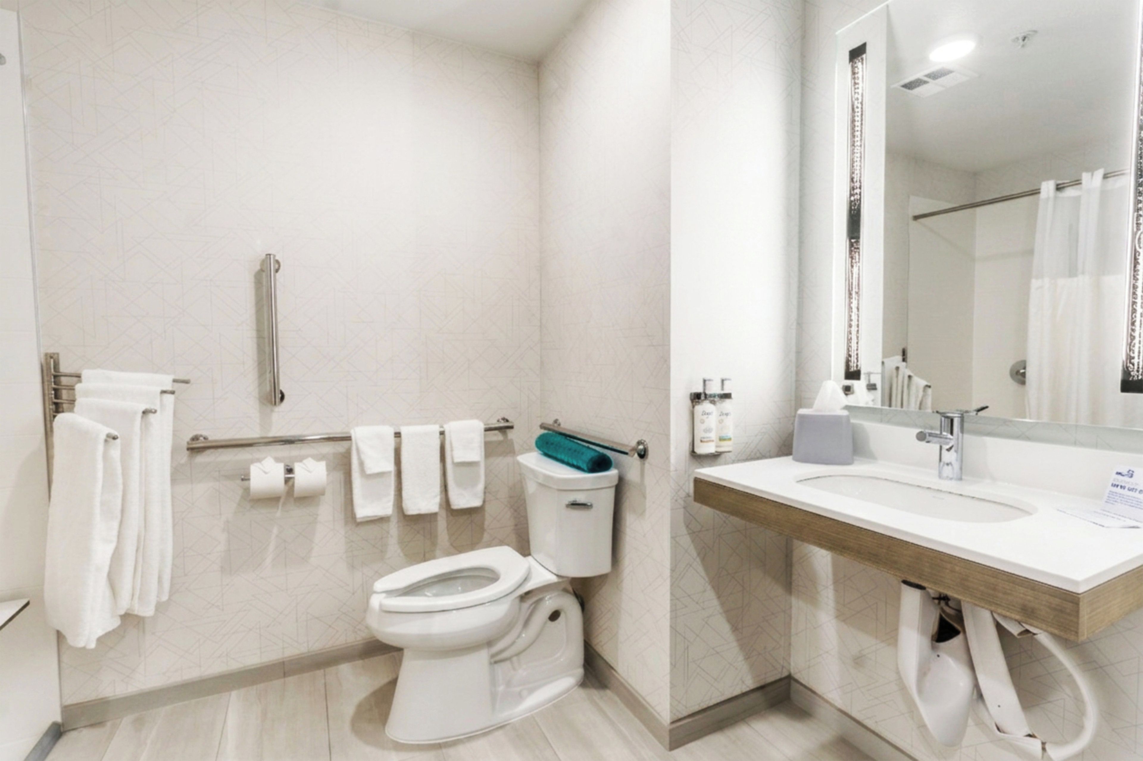 Une salle de bain moderne équipée de toilettes, d’un bidet, d’un sèche-mains et d’un grand miroir.