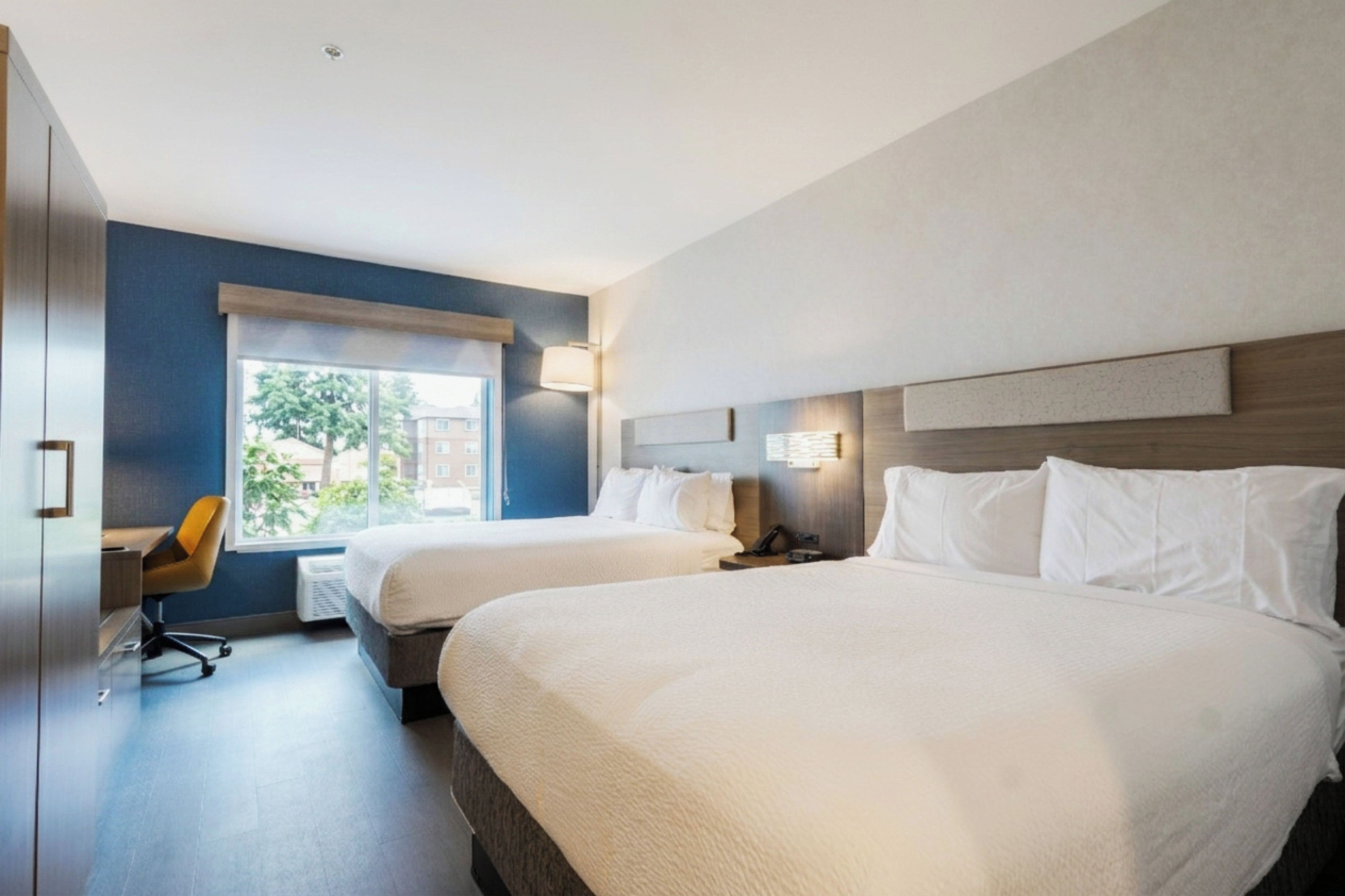 Une chambre d’hôtel avec deux lits, un bureau et une chaise.