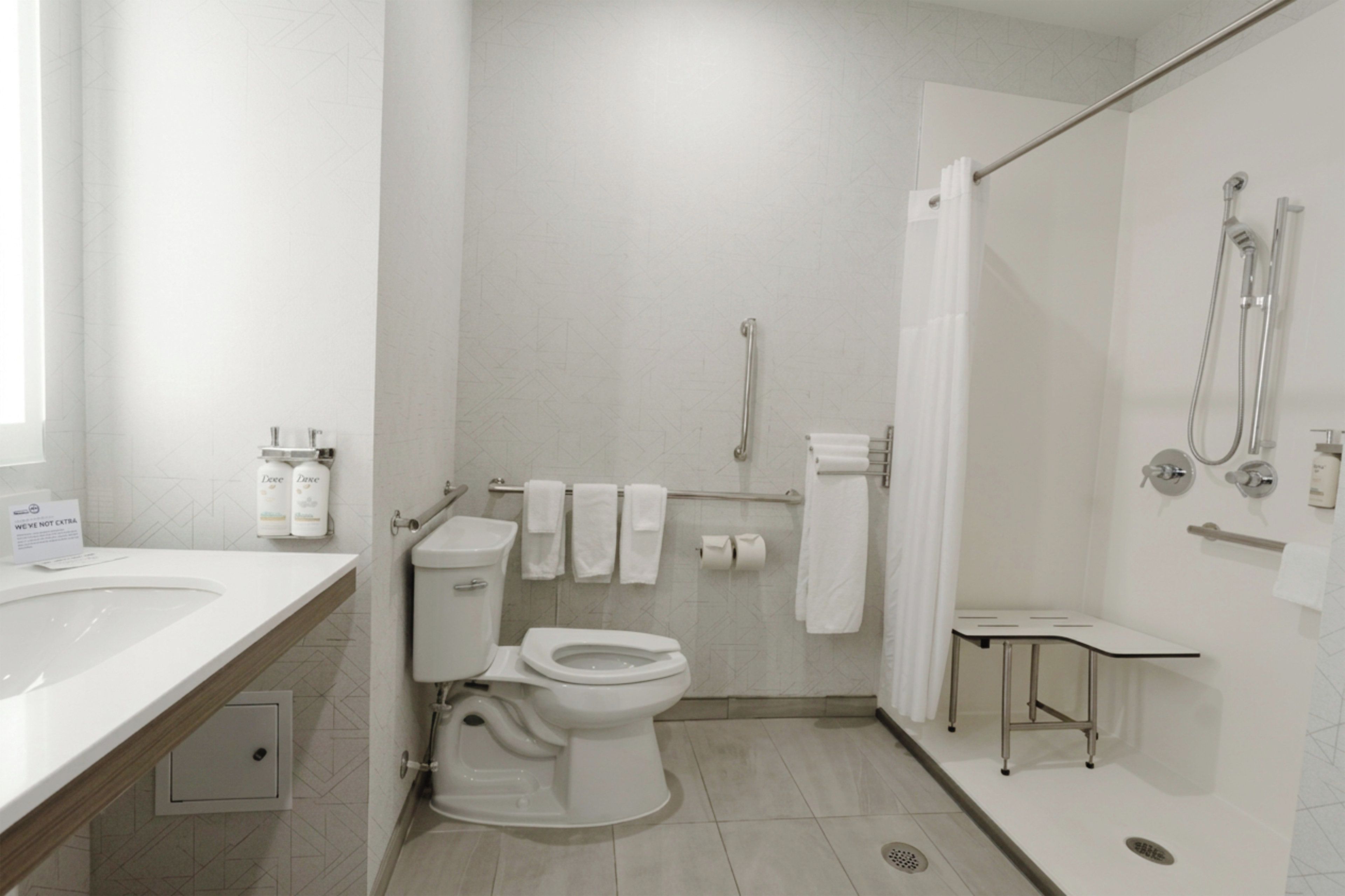 A modern bathroom with a toilet, bidet, and shower. There are towels and toiletries on the wall.