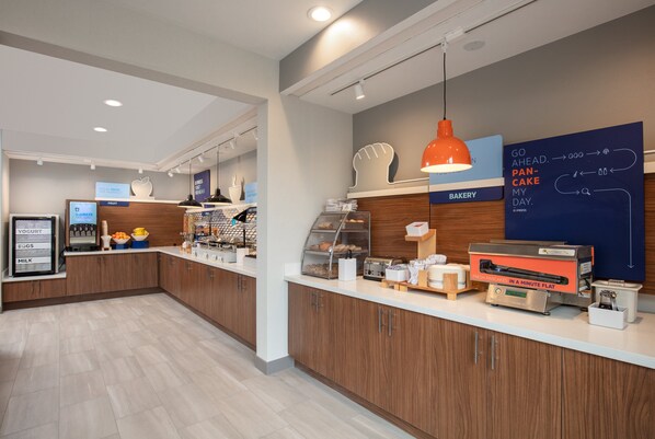 A modern kitchen area with a bakery section, a coffee machine, and a sign indicating fresh pastries. - Holiday Inn Express Bothell by IHG (Bothell)