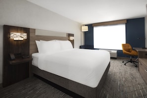 Habitación de hotel con una cama grande, un escritorio con silla, una mesita de noche y una ventana con vistas.