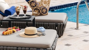 Zona de descanso junto a la piscina con mesa, cesta y vistas al agua.