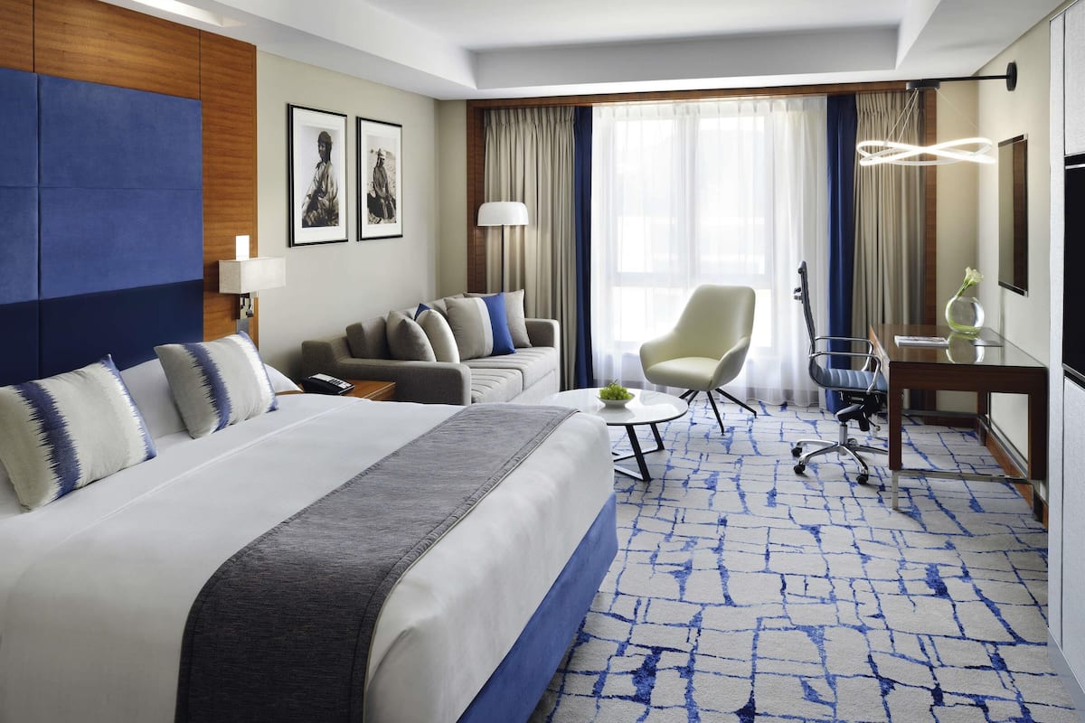 Una habitación de hotel con una cama grande, un sofá, un escritorio y una silla.