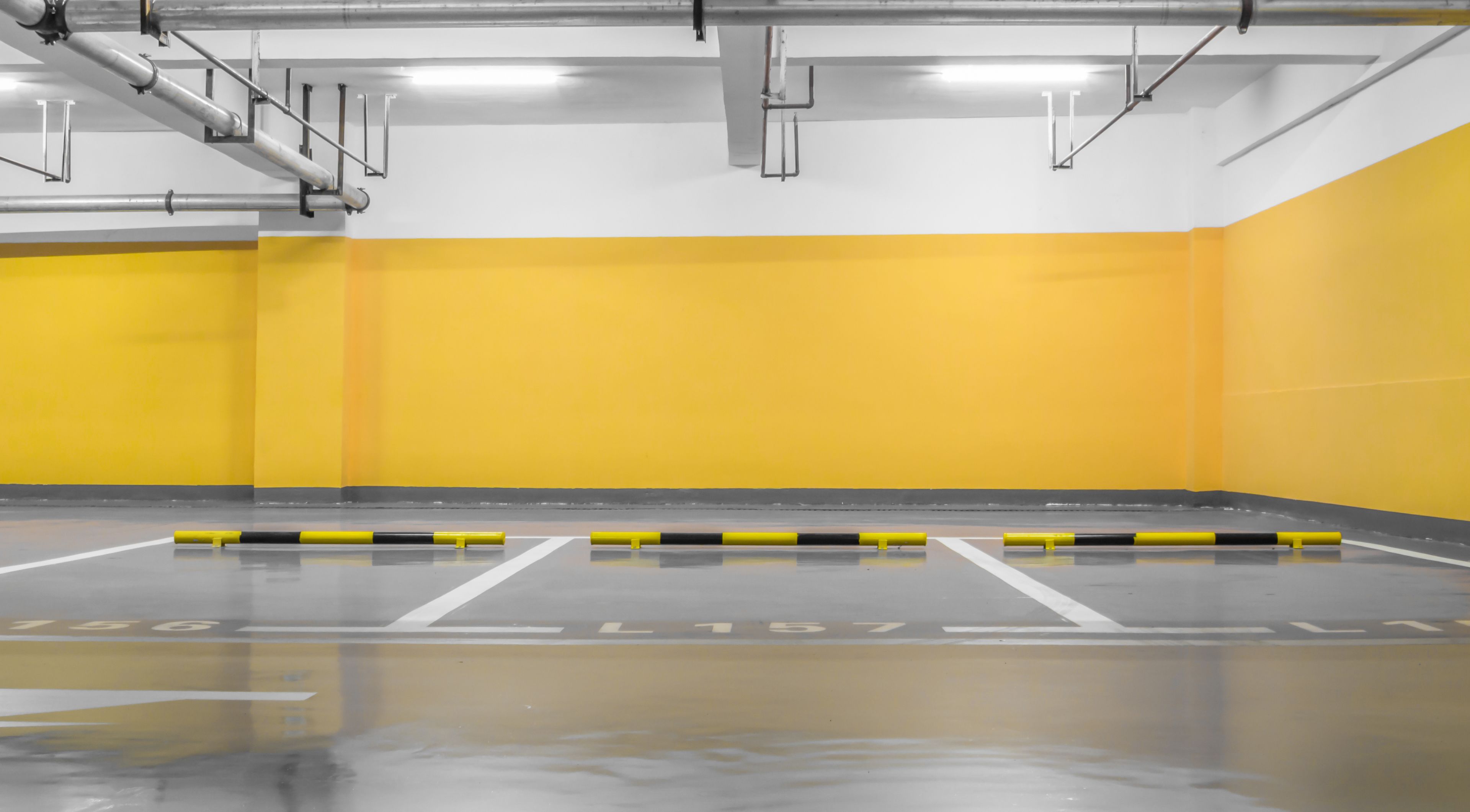 A parking garage with yellow walls and white floor markings.