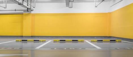 A parking garage with yellow walls and white floor markings.