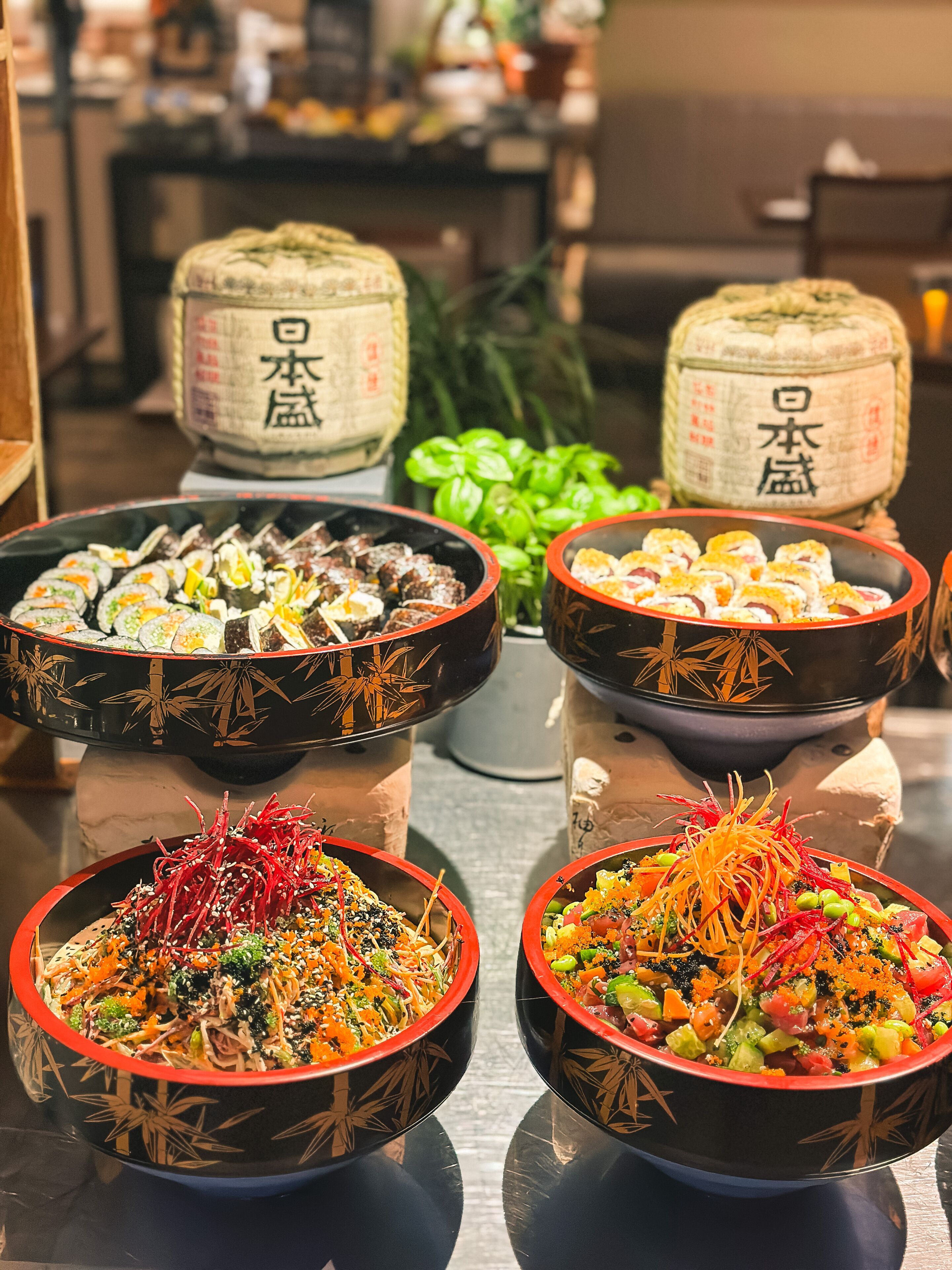 A table with various dishes, including sushi and salads, in decorative bowls.