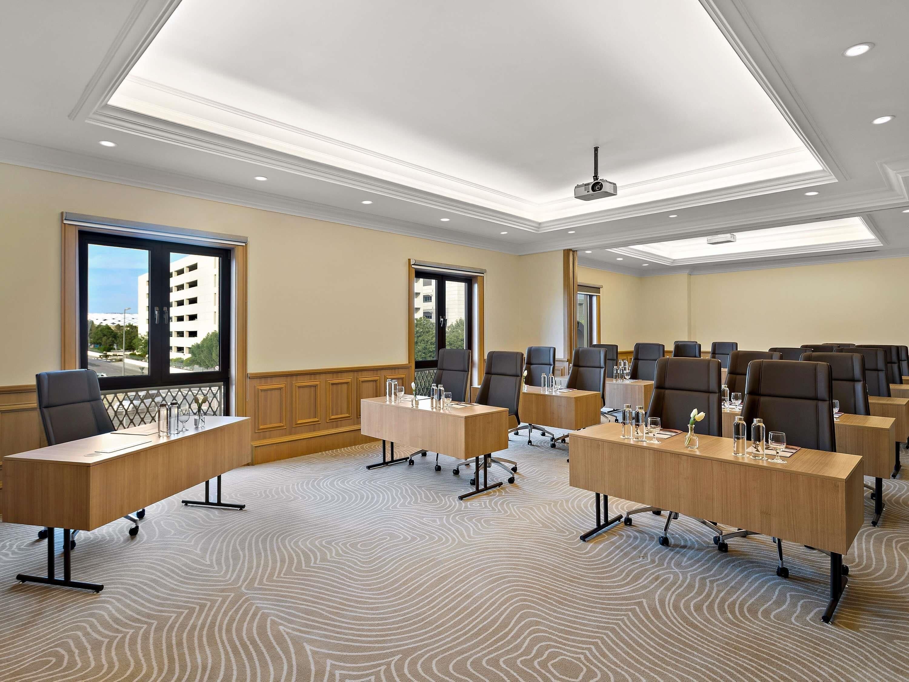 A conference room with multiple tables, chairs, and a ceiling projector.