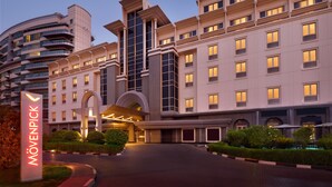Un hotel moderno con una entrada destacada, varios pisos y una fachada bien iluminada.