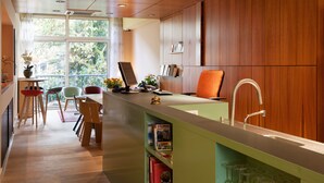 A modern kitchen with a wooden countertop, a sink, and a window overlooking greenery. - Hotel The Neighbour's Magnolia (Amsterdam)