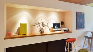 A reception desk with a computer, a vase with branches, and two bar stools. - Hotel The Neighbour's Magnolia (Amsterdam)