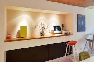 A reception desk with a computer, a vase with branches, and two bar stools.