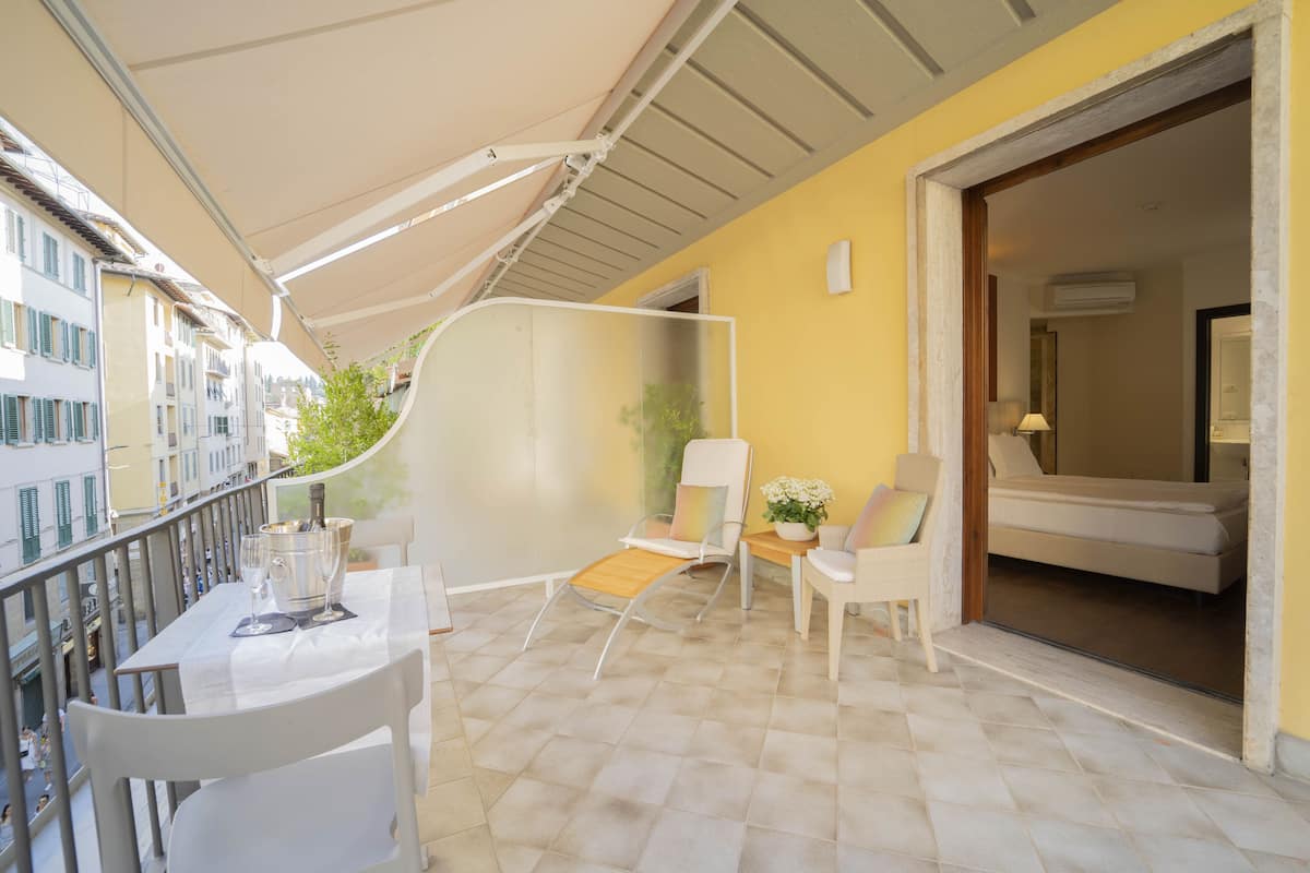 A balcony with a table, chairs, and a potted plant.