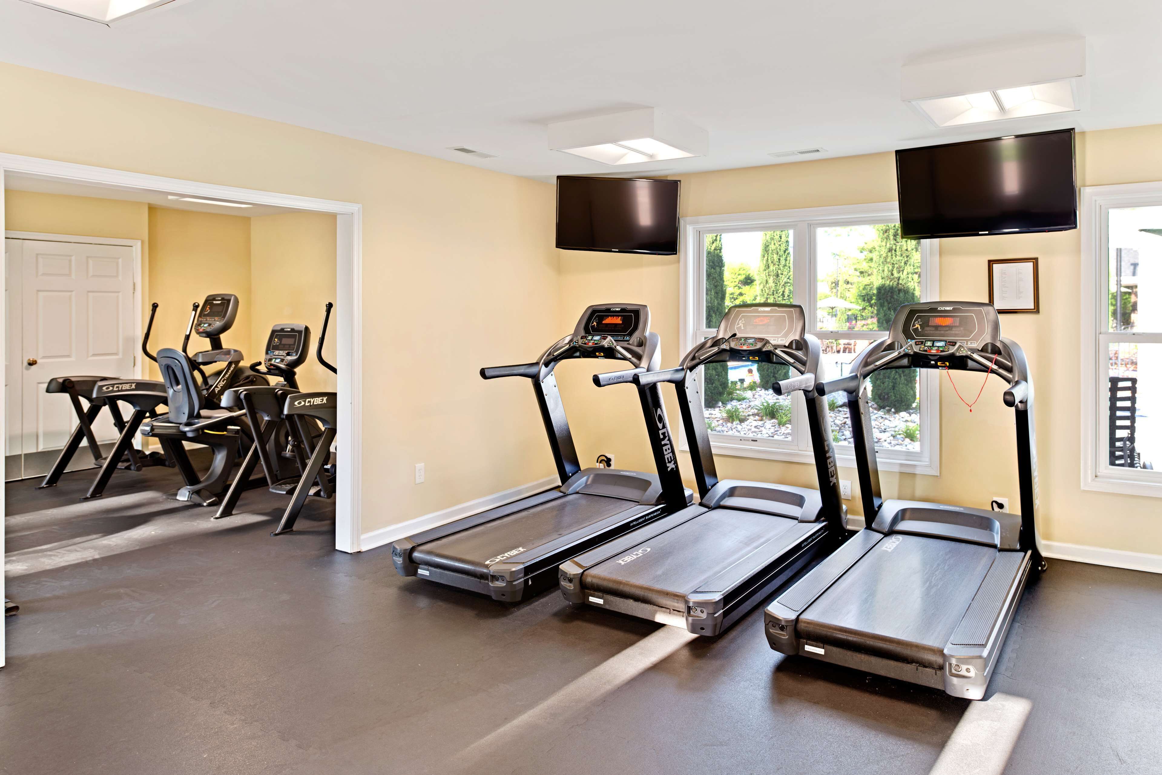 A gym with treadmills, exercise bikes, and a TV mounted on the wall.