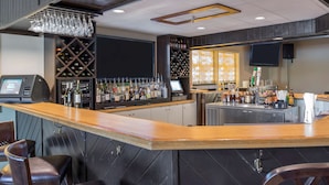 Un espace bar avec un comptoir en bois, des étagères à vin et des sièges.