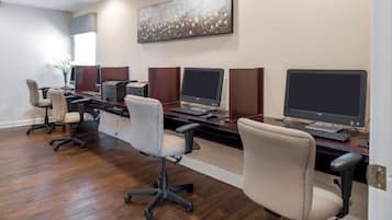 Une salle de conférence équipée de quatre bureaux, chacun comprenant un ordinateur et une chaise.