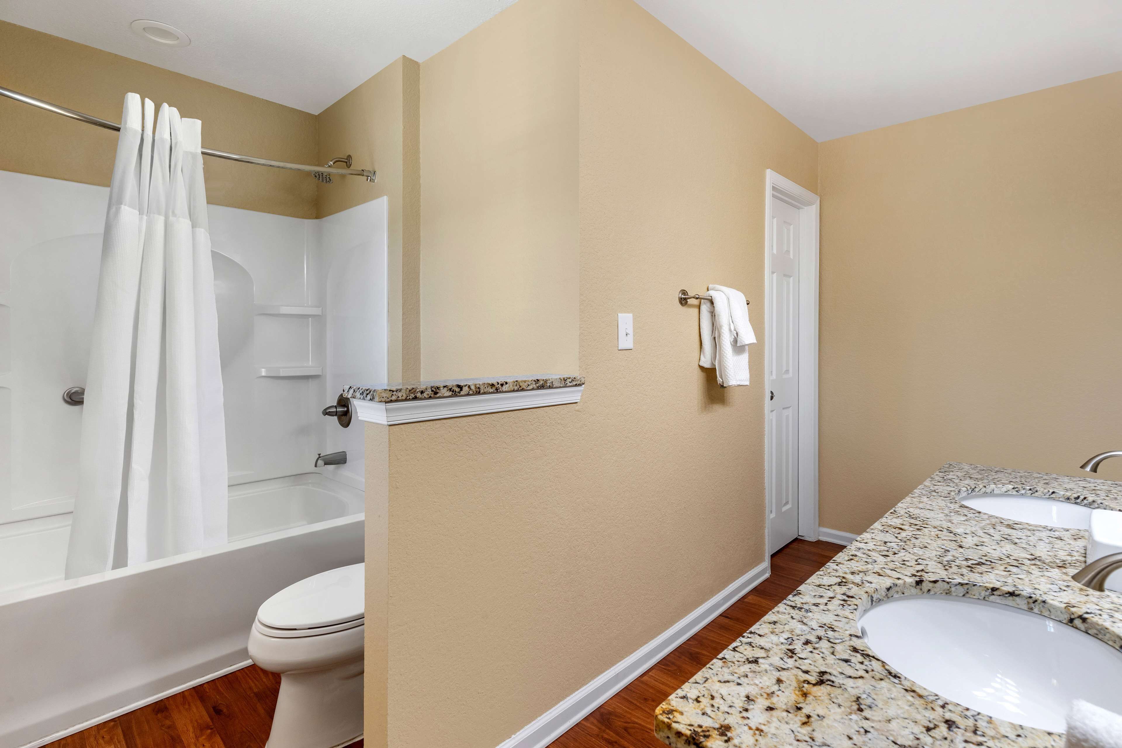 A bathroom with a bathtub, toilet, and two sinks.