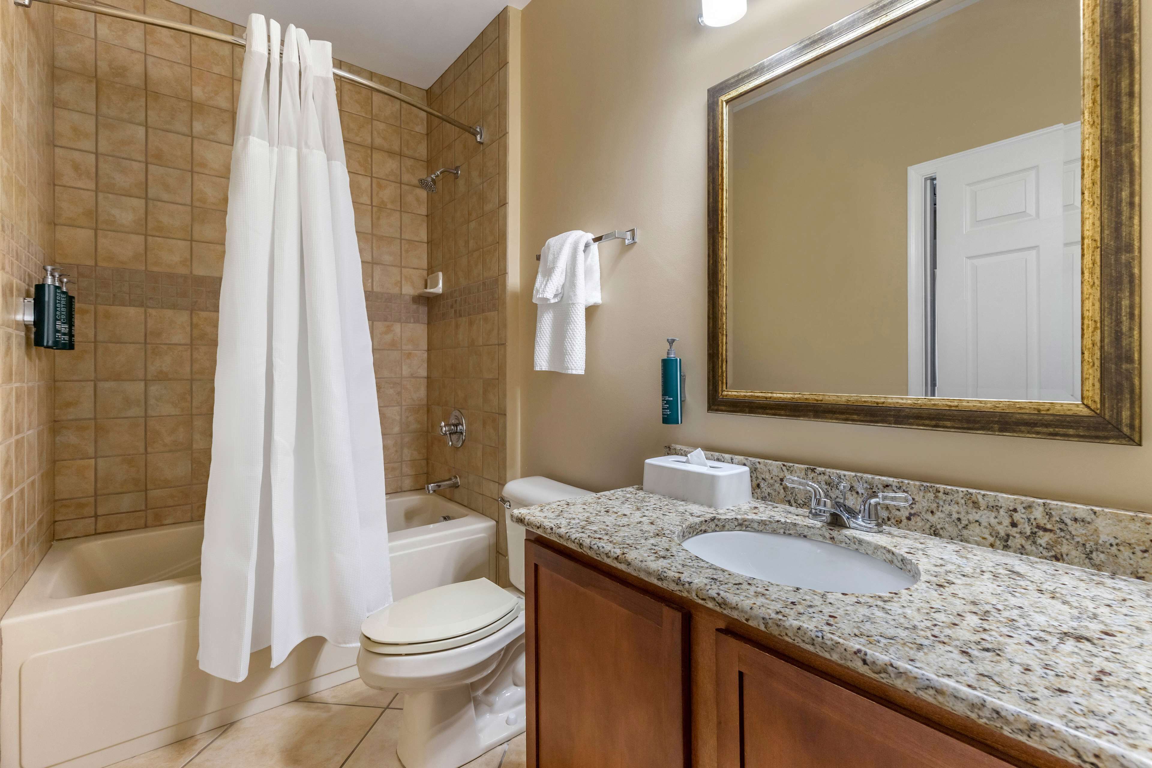 A bathroom with a bathtub, toilet, sink, and a large mirror.