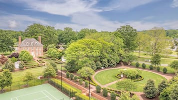 Un grand bâtiment en briques, entouré de jardins bien entretenus et d’un court de tennis.