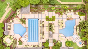 Vue aérienne d’un complexe hôtelier doté de plusieurs piscines, de chaises longues et de jardins aménagés.