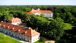 Ein großes Gebäude mit rotem Dach, umgeben von üppiger Vegetation und Bäumen.