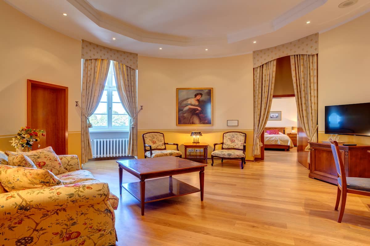 Amplia sala de estar con un sofá, una mesa de centro de madera, dos sillones, un televisor y un cuadro en la pared.